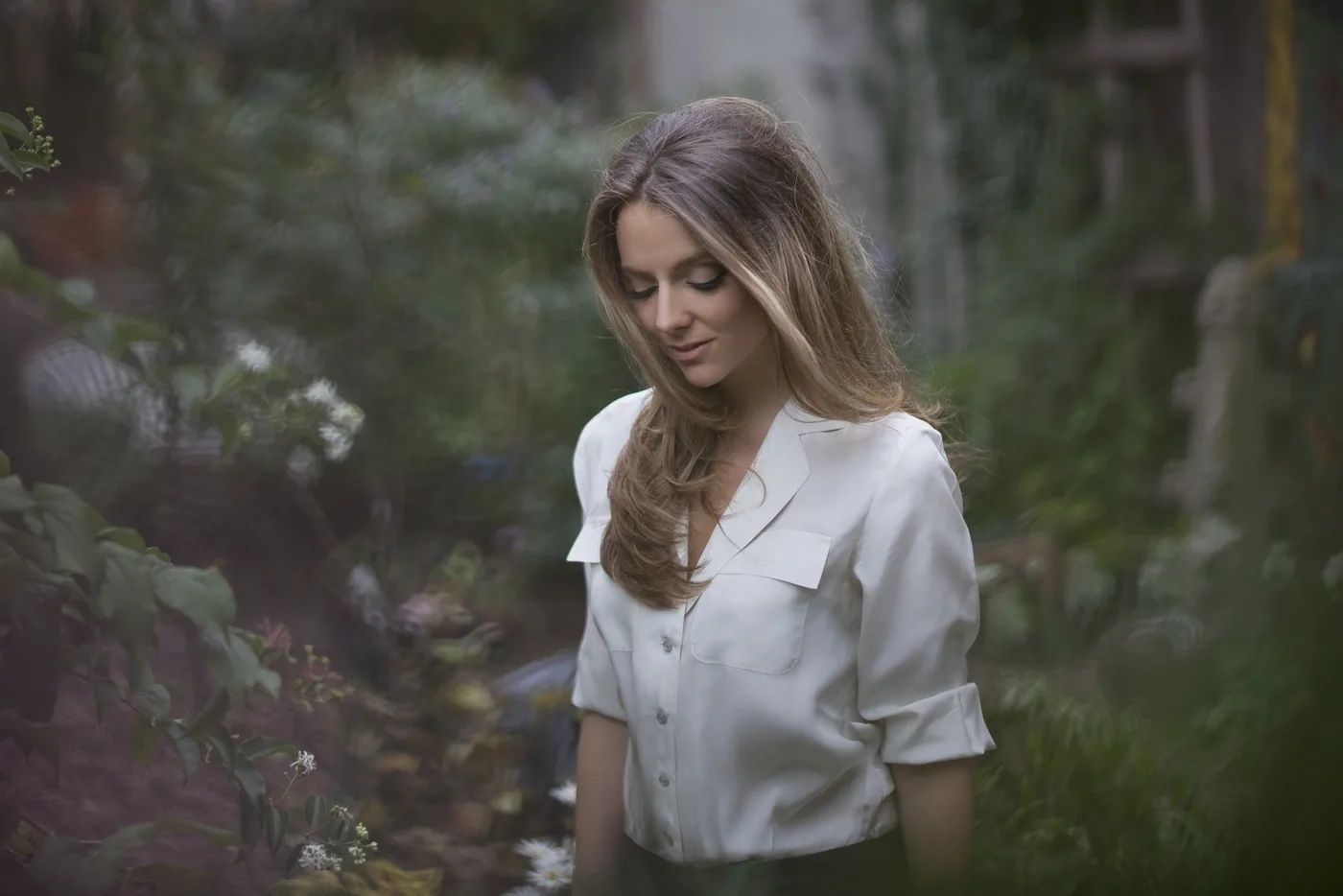 Violette in a garden, wearing a white shirt